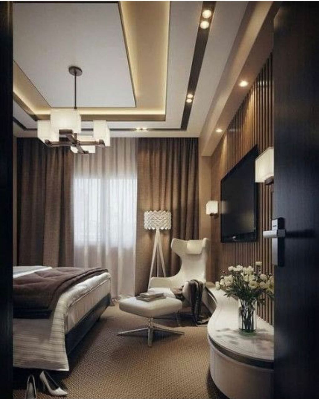 Elegancka sypialnia w beżach: designerski fotel, lampa podłogowa, kwiaty na stoliku. Podwieszany sufit z oświetleniem LED. Minimalistyczny żyrandol.