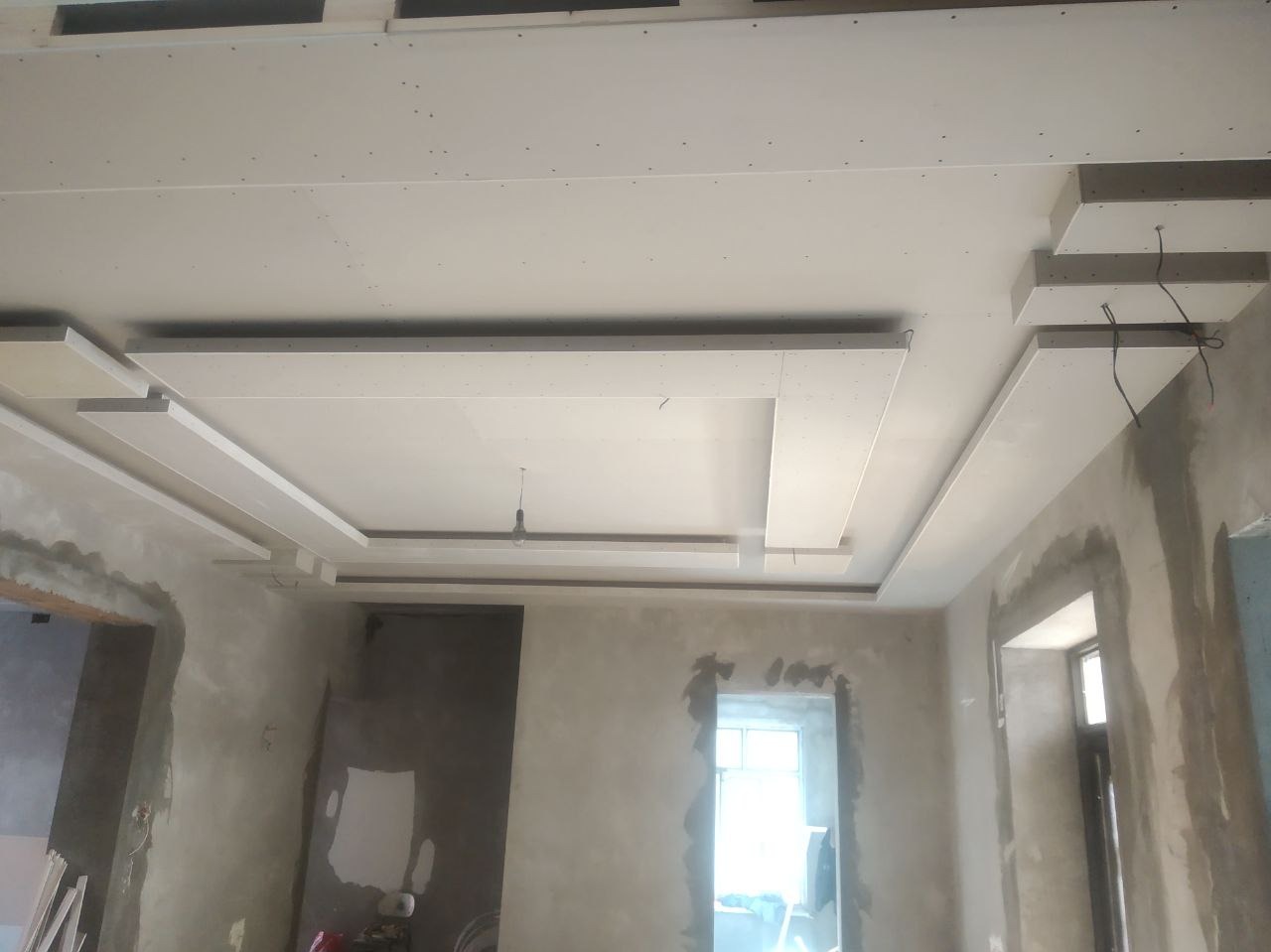 Sufit podwieszany z płyt karton-gips w trakcie montażu we Wrocławiu. Widoczne elementy konstrukcyjne i surowy stan ścian.