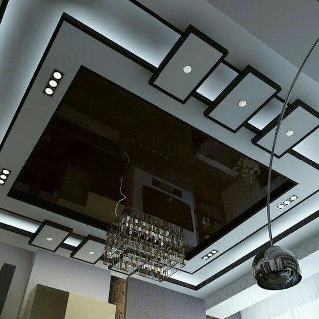 Nowoczesny sufit podwieszany z czarnym lustrzanym panelem, oświetleniem LED i designerskim żyrandolem. Geometryczne wzory i eleganckie wykończenie.