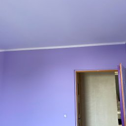 Bud_Job - Fioletowe ściany i sufit po malowaniu, biała listwa sufitowa, widok na futrynę drzwiową. Świeżo pomalowane wnętrze z widoczną strukturą farby.