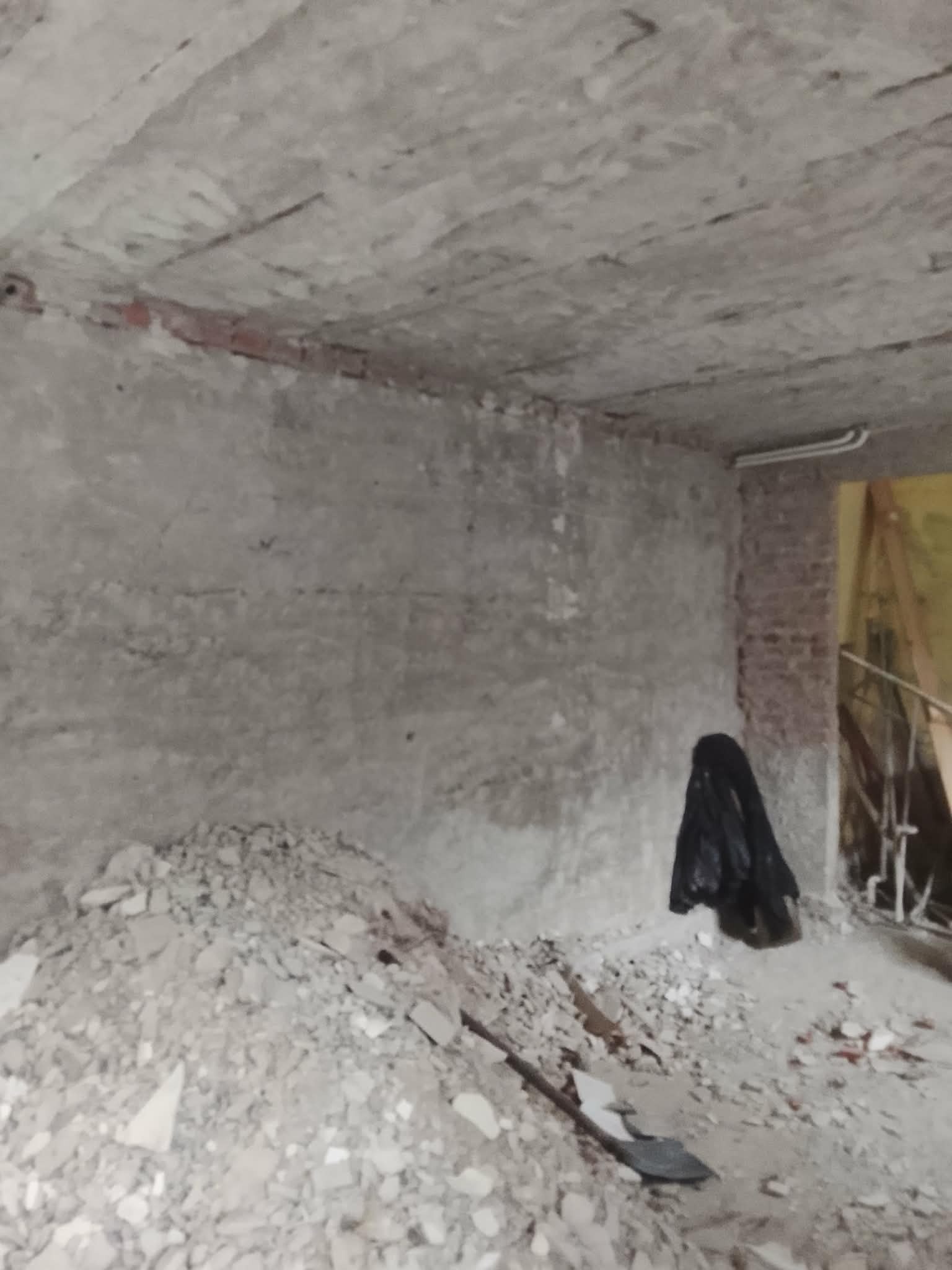 Wnętrze w trakcie rozbiórki: gruz na podłodze, ściany z odsłoniętą cegłą, widoczny fragment instalacji elektrycznej pod sufitem. Etap prac przygotowawczych do remontu.