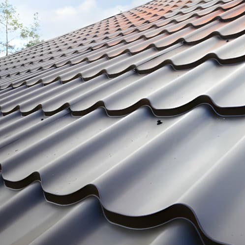 Szary dach z blachy trapezowej, widok z dołu pod kątem. Widoczne połączenia arkuszy i fragment nieba w tle. Nowoczesne pokrycie dachowe.