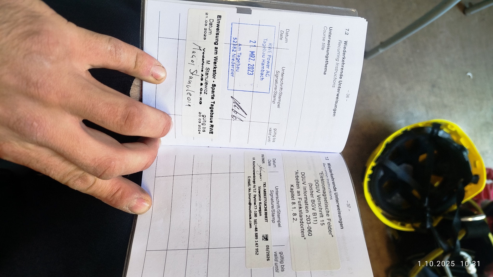 Książeczka z wpisami szkoleń BHP, widoczny stempel RWE Power AG i podpis. Obok leży żółty kask ochronny. Dokumentacja potwierdzająca kwalifikacje.