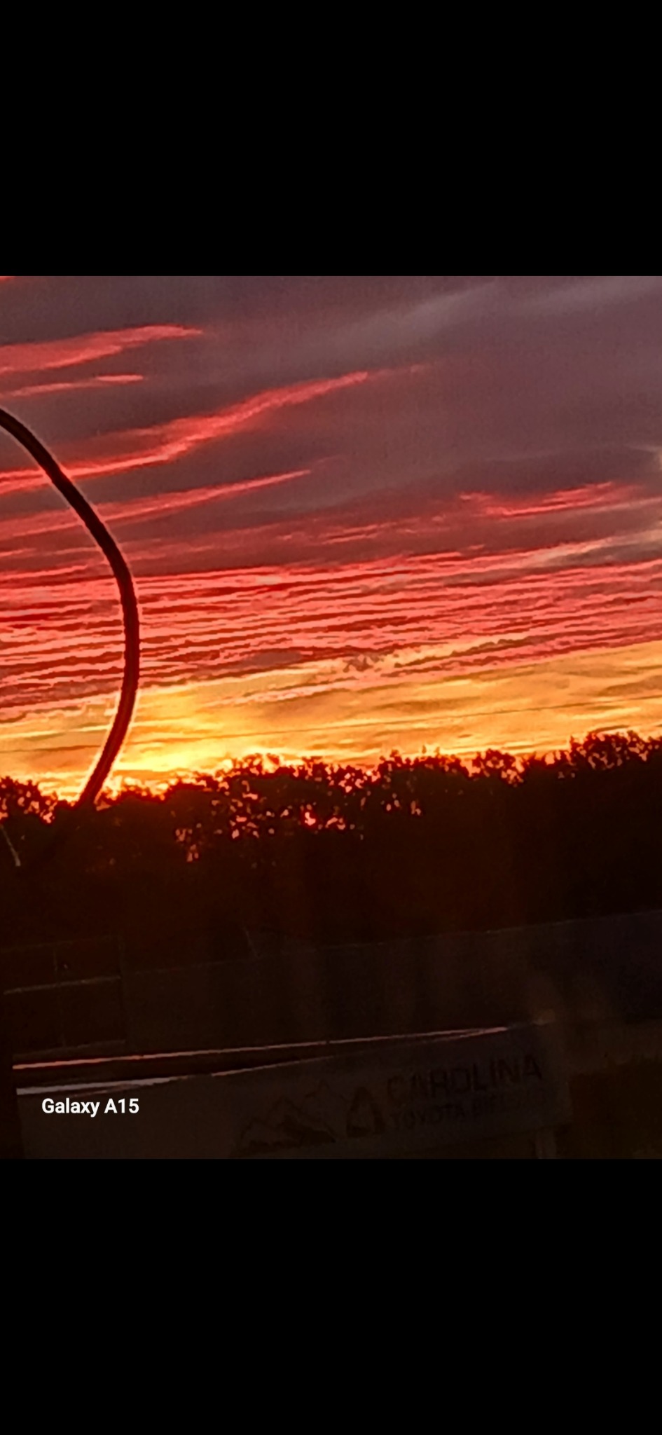 Kabel energetyczny na tle wschodzącego słońca w Czechowicach-Dziedzicach. Widoczne drzewa i pomarańczowo-czerwone niebo o świcie. Fragment kabla po lewej stronie kadru.
