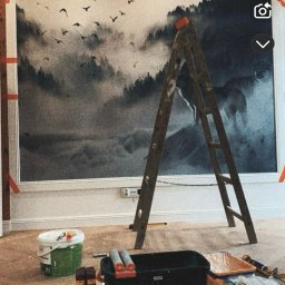 Z.U.H Jakub Sitarski - Malowanie ściany z motywem leśnym. Widoczna drabina, kuweta malarska i wałki. Prace wykończeniowe w pomieszczeniu z beżową podłogą i białymi listwami przypodłogowymi.