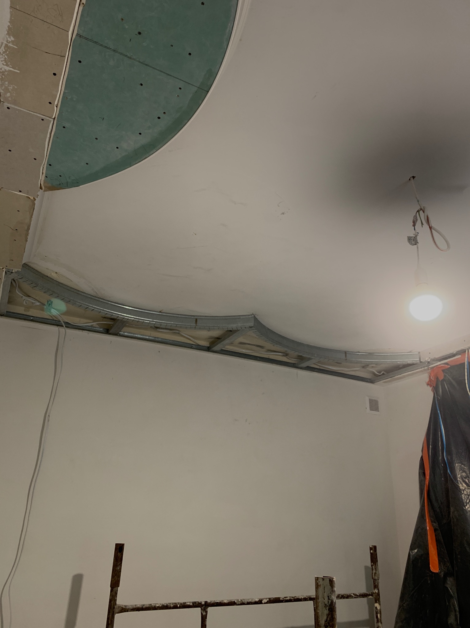 Montaż sufitu podwieszanego z płyty G-K na metalowym stelażu w Zielonej Górze. Widoczne elementy konstrukcyjne i fragment płyty. Oświetlenie robocze.