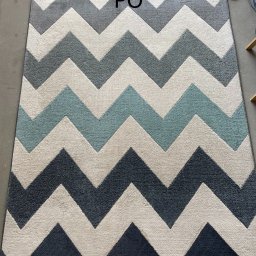 ABSmartClean - Wyczyszczony dywan w zygzaki, odświeżony po praniu, z widocznym napisem 'PO' sugerującym efekt końcowy usługi czyszczenia.