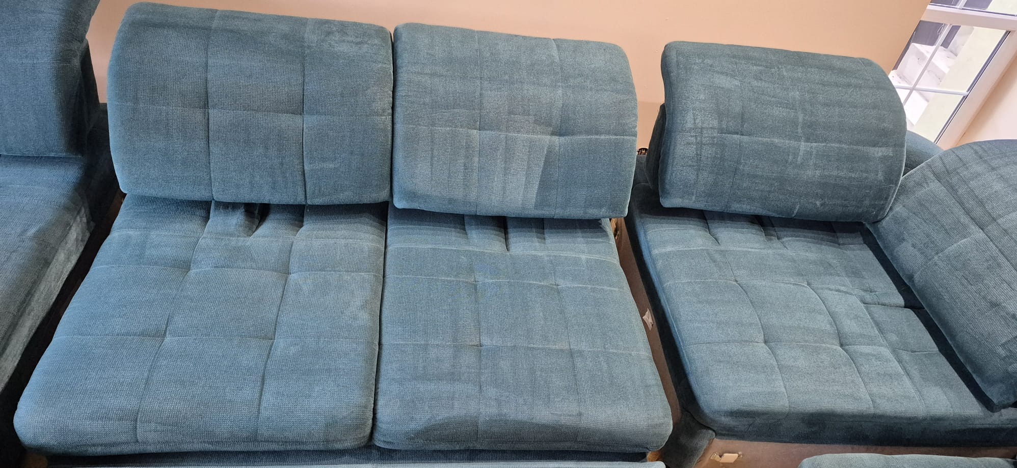 Turkusowa sofa modułowa z wyraźnymi śladami po czyszczeniu tapicerki, ukazująca różnicę w odcieniu i strukturze materiału po zabiegu.