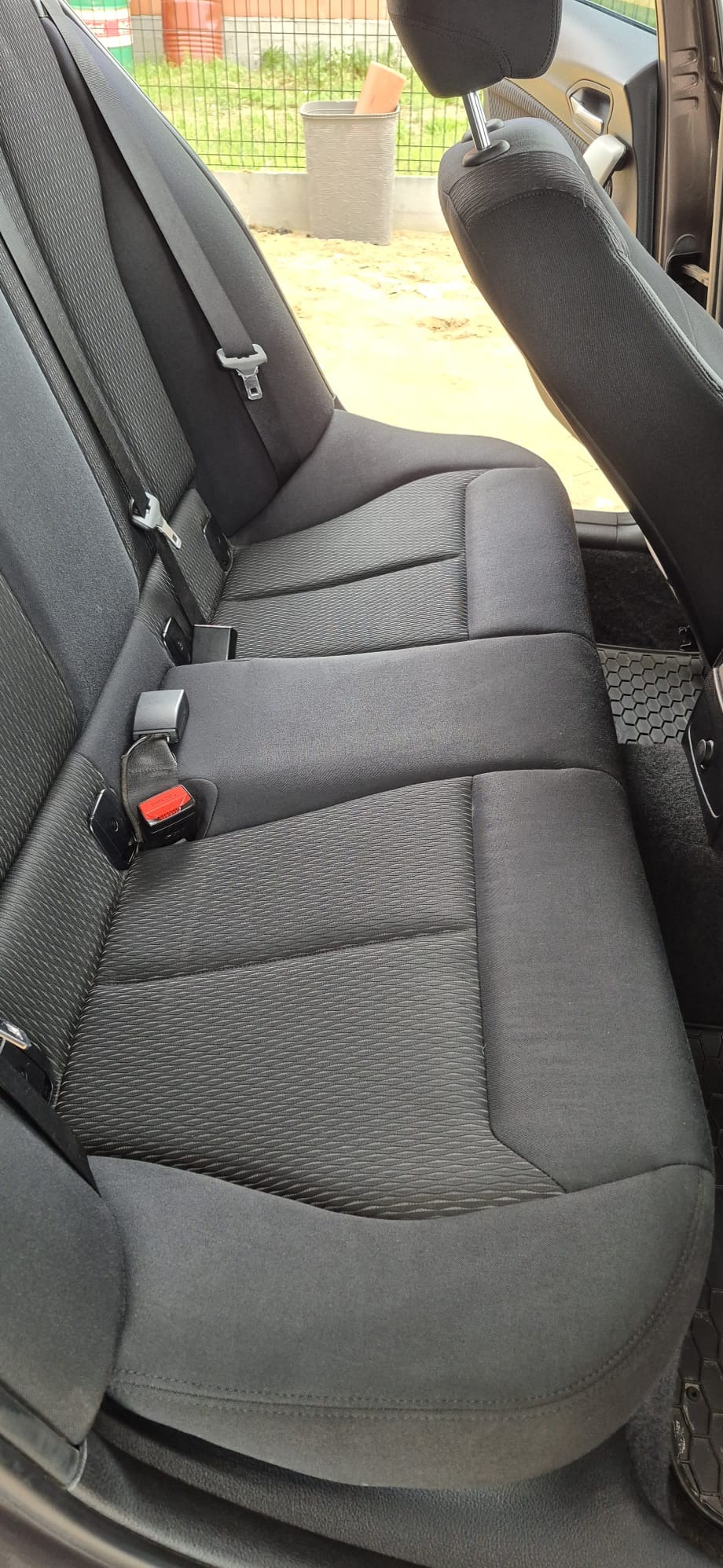 Czarne, tekstylne siedzenie samochodowe z pasami bezpieczeństwa, widok z góry. Czysta tapicerka po usłudze czyszczenia.