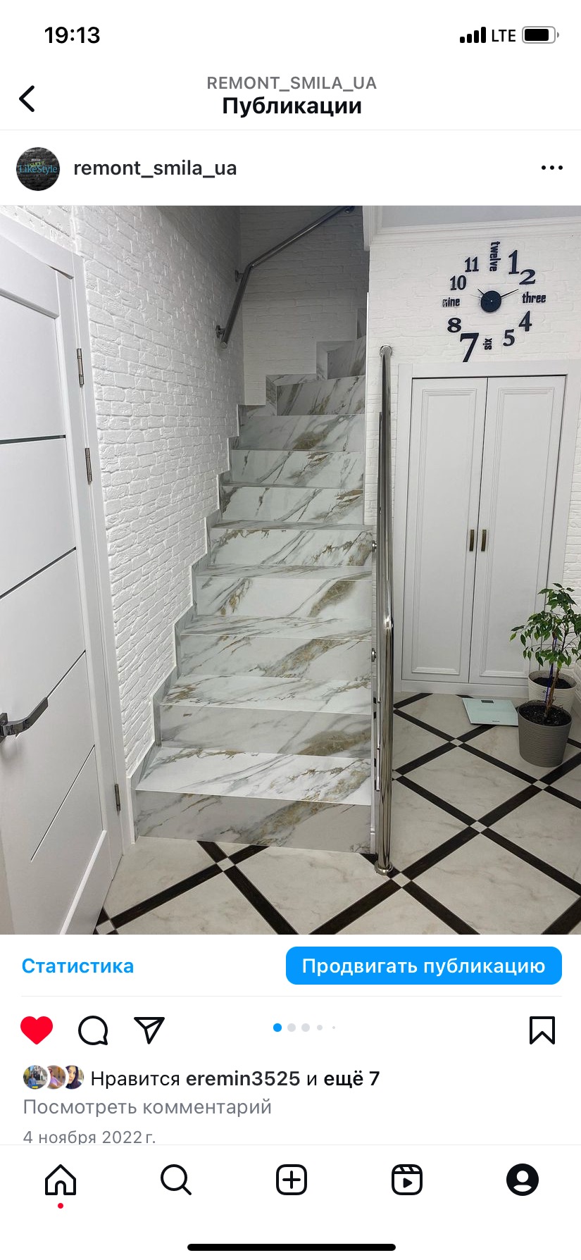 Wykończone schody z marmurowym wzorem i metalową barierką, biała ściana z cegły, dekoracyjny zegar i podłoga w szachownicę. Nowoczesne wykończenie wnętrza.