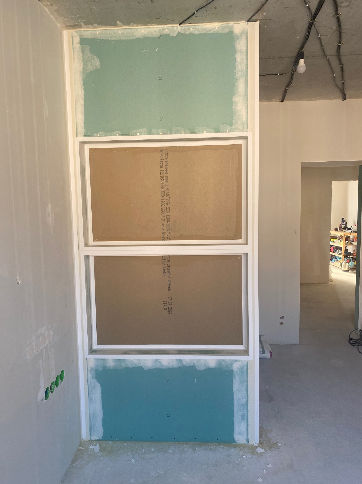 Konstrukcja z płyt gipsowo-kartonowych w trakcie montażu, widoczne profile i płyty w różnych odcieniach, surowy stan wnętrza, przygotowanie do dalszych prac wykończeniowych.