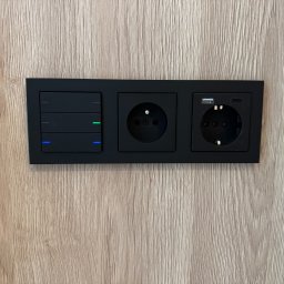 AUTOMATYK SP. Z O.O - Czarny panel z włącznikami światła, gniazdkiem elektrycznym i USB-C na drewnopodobnej ścianie. Nowoczesny design, minimalistyczny styl, oświetlenie LED.