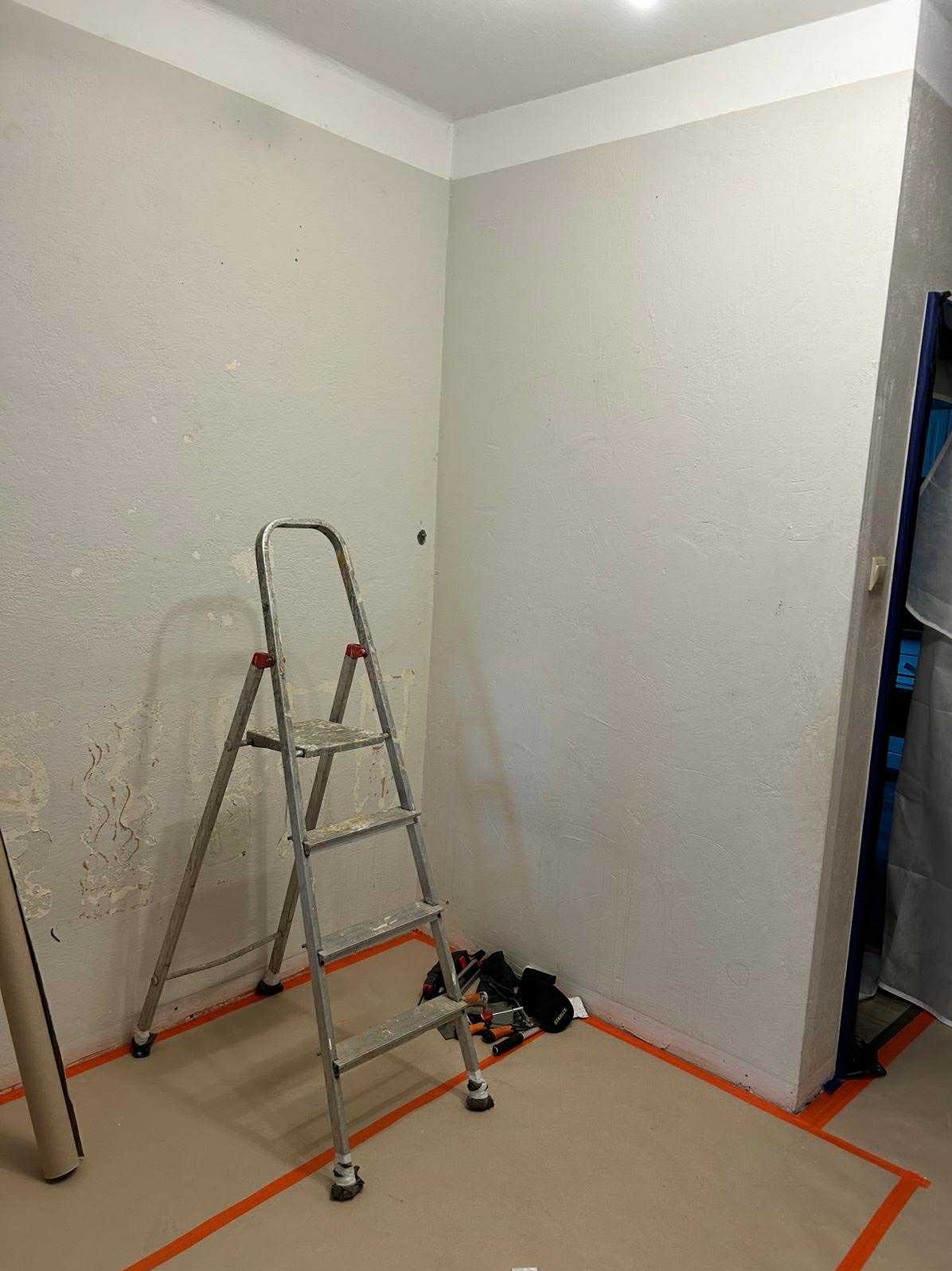 Przygotowanie do malowania ścian w Łowiczkach: drabina, zabezpieczona podłoga i ściany z widocznymi śladami po usuniętej tapecie, gotowe do dalszych prac wykończeniowych.