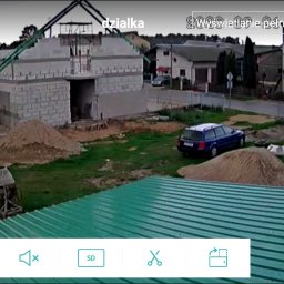 Robert Jórkowski - Budowa domu z bloczków, widok z góry na plac budowy z zaparkowanym samochodem. Widoczna betoniarka i hałdy piasku. Ujęcie z kamery monitoringu.