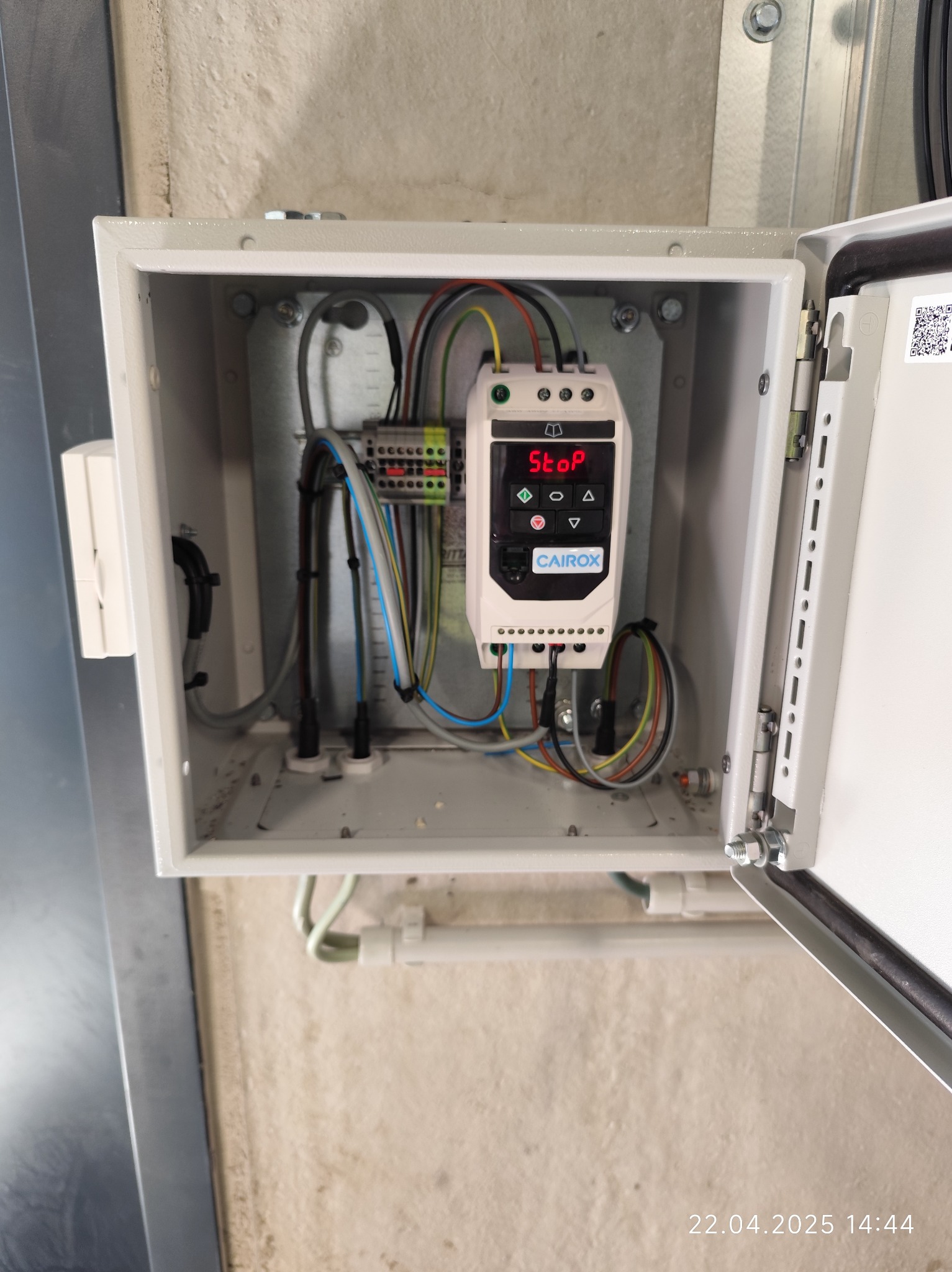 Otwarta skrzynka elektryczna z widocznym sterownikiem CAIROX i podłączonymi przewodami. Widoczne złącza i elementy instalacji.