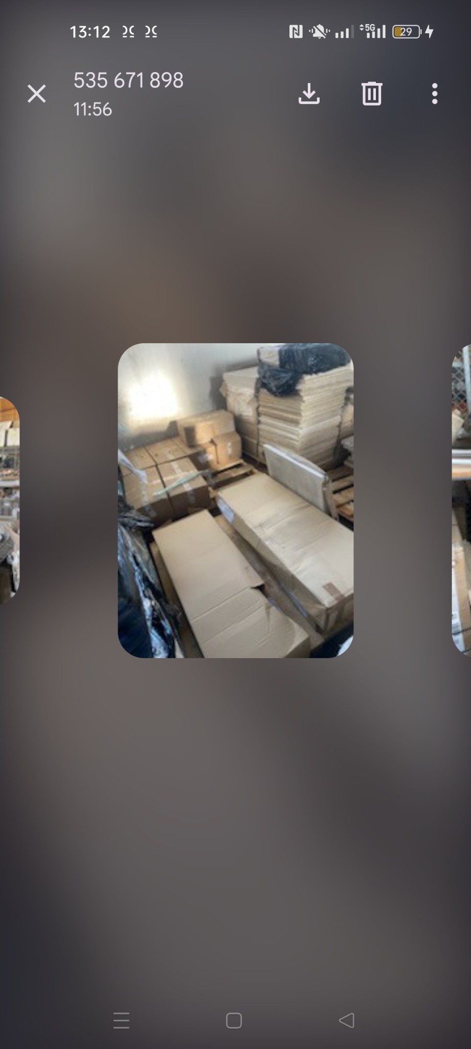 Kartonowe pudła i worki składowane w pomieszczeniu. Część przedmiotów na paletach. Magazyn z rzeczami przygotowanymi do wywozu.