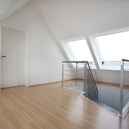 Kuba kępski - Jasne poddasze po remoncie: drewniana podłoga, białe ściany, schody z metalową barierką i dwa okna dachowe w skosie. Minimalistyczny design.