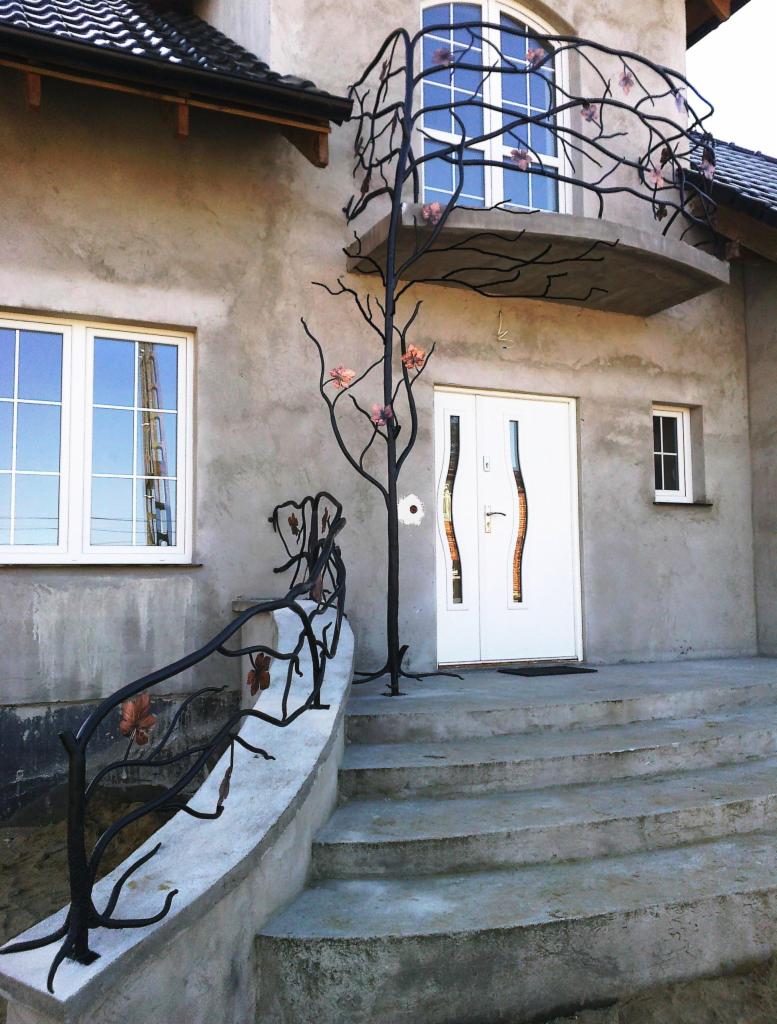 Kute balustrady w kształcie drzewa z miedzianymi liśćmi zdobią schody i balkon domu. Nietypowy, artystyczny design. Elementy metalowe w kolorze czarnym.