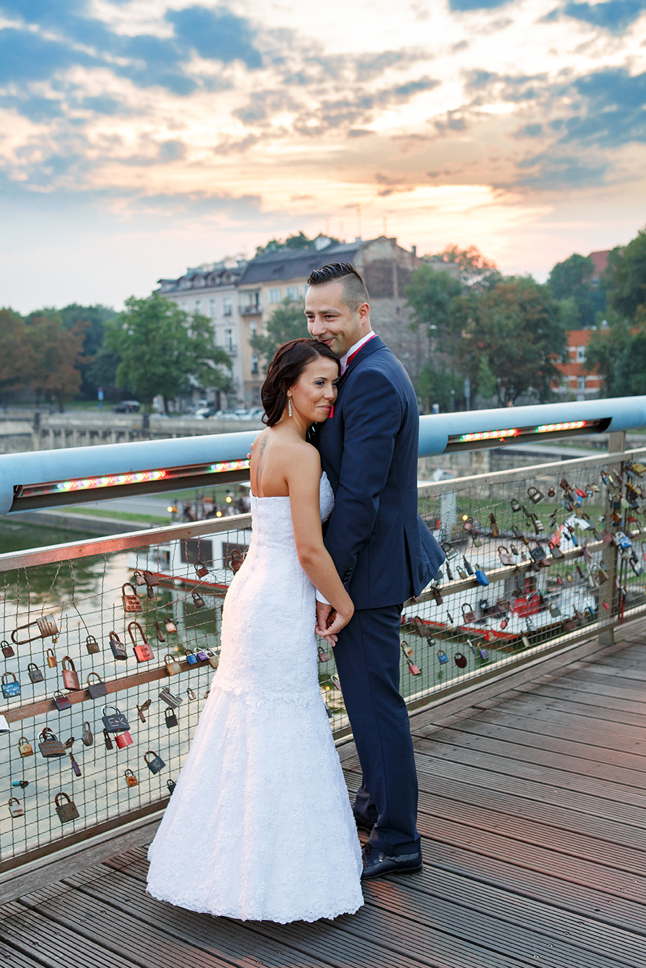 Para młoda na moście zakochanych, wieczorne światło, widok na miasto w tle. Most ozdobiony kłódkami symbolizującymi miłość.