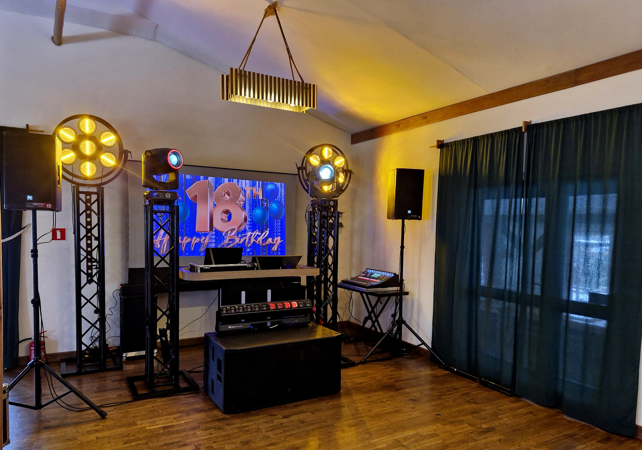 Scena z nagłośnieniem i oświetleniem na 18 urodziny. Widoczne kolumny, reflektory, mikser i ekran z napisem 'Happy Birthday'.