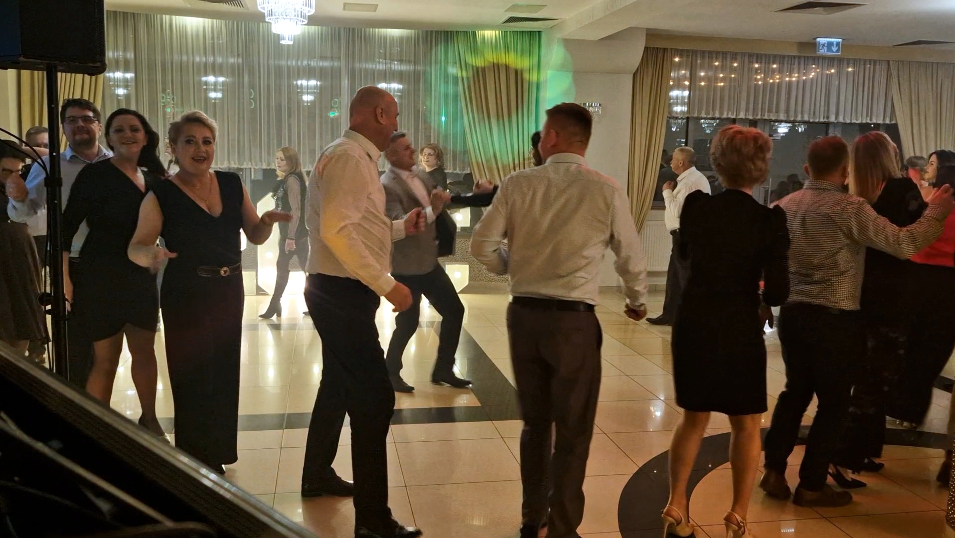 Roztańczeni goście weselni na parkiecie, widoczne osoby w ruchu, dekoracje sali, światła i parkiet. Ujęcie z perspektywy DJ-a lub zespołu.