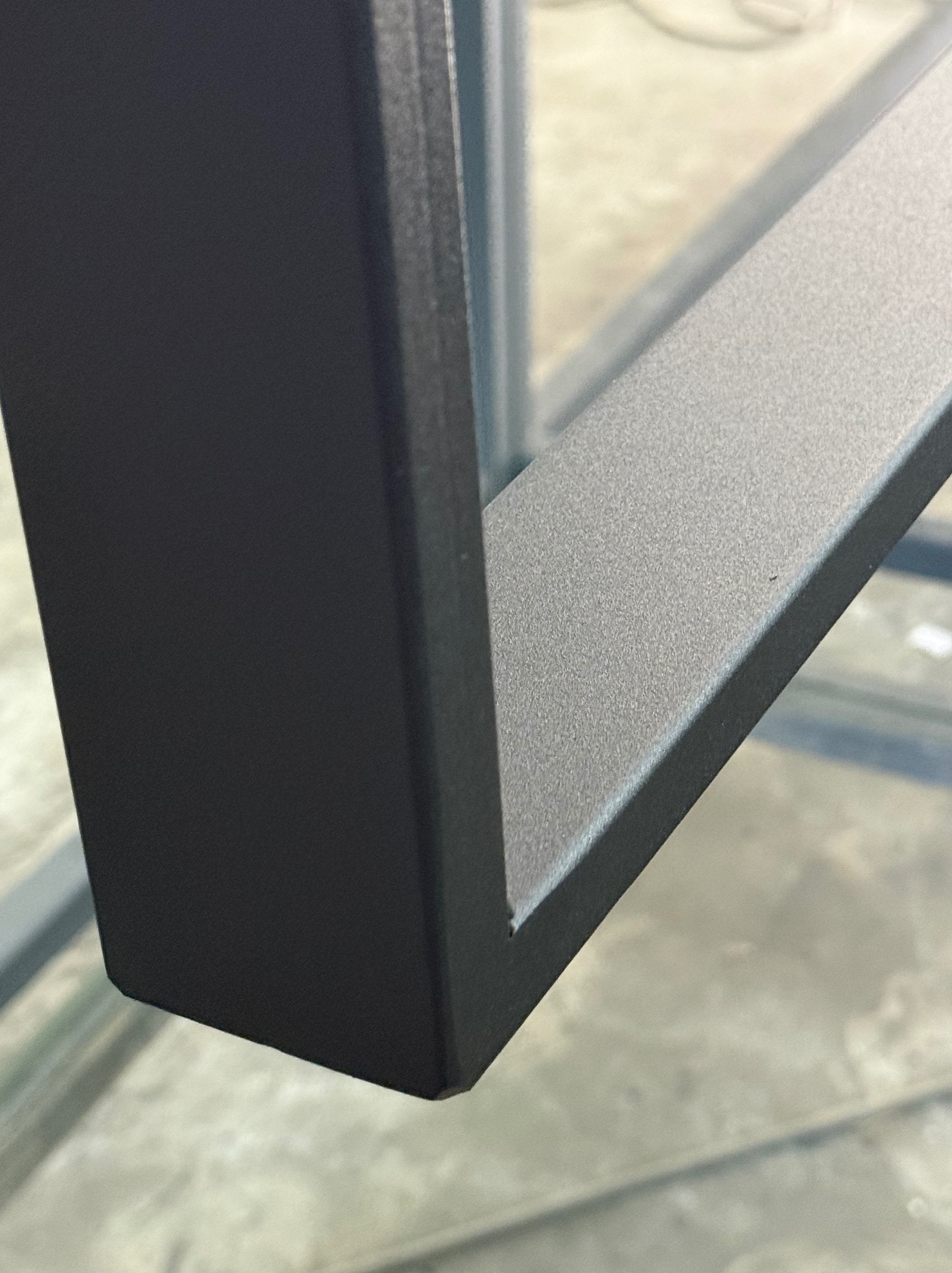 Detaliczny widok narożnika metalowej konstrukcji, prawdopodobnie balustrady, z widoczną fakturą i precyzyjnym wykończeniem powierzchni.