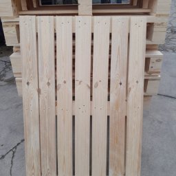 Palety Fitosanitarne I SPRZEDAŻ TARCICY LESZEK MICHALIK - Jasna, drewniana paleta z widocznym rysunkiem słojów, ułożona na stosie innych palet. Widoczne gwoździe i naturalna struktura drewna.