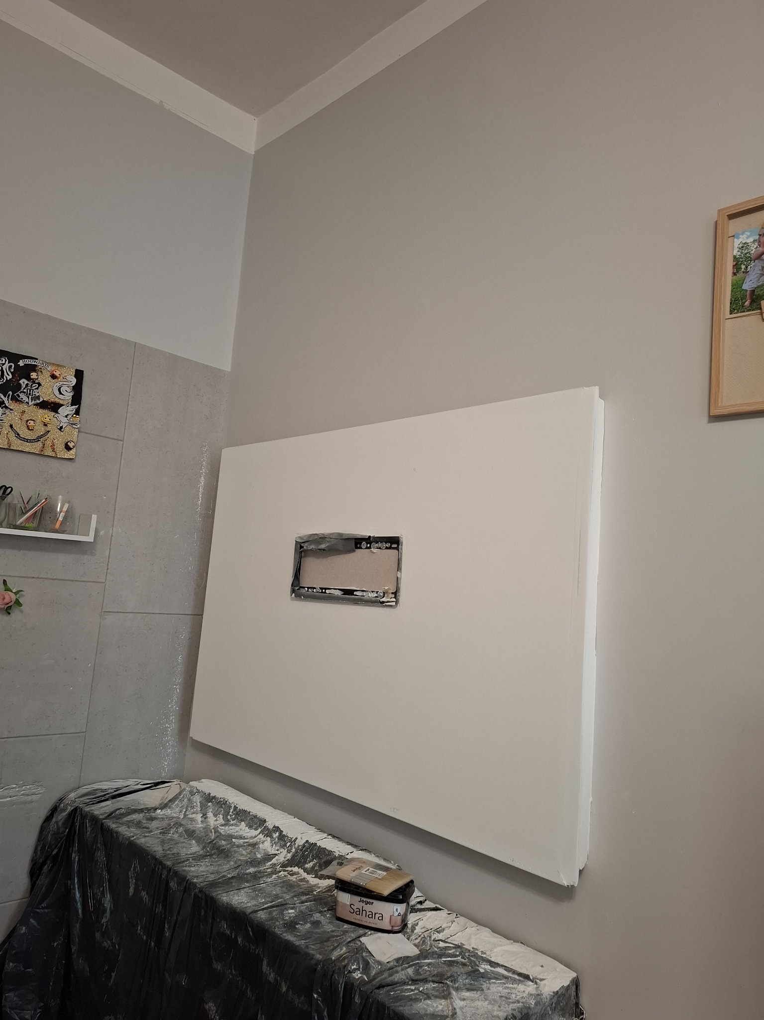 Płyta karton-gips z otworem na ścianie, przygotowana do szpachlowania. Pod spodem zabezpieczona folią i karton gipsu Sahara. Widoczne ślady po szpachlowaniu.
