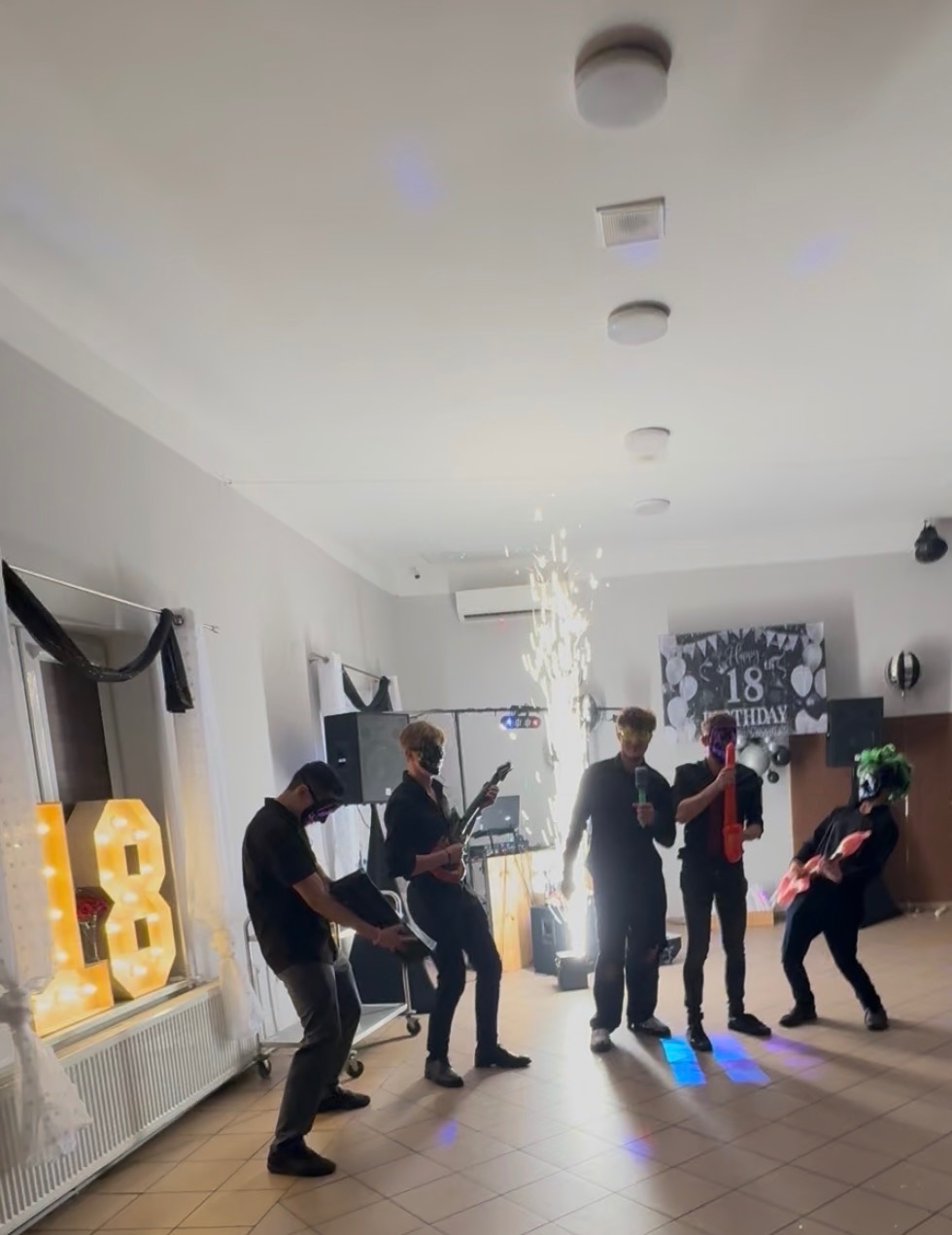 Zespół w maskach gra na 18 urodzinach, z efektami pirotechnicznymi. Dekoracja z podświetlonym numerem 18. Nietypowy występ na imprezie.