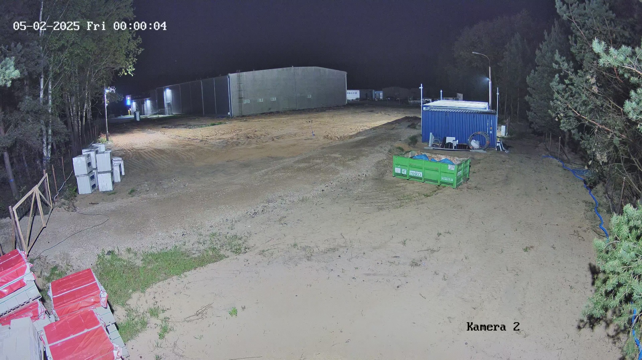 Nocny widok z kamery monitoringu w Częstochowie, obejmujący teren budowy z kontenerem, materiałami budowlanymi i budynkiem w tle. Widoczna data i oznaczenie kamery.