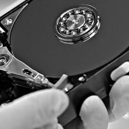 iTechData - Odzyskiwanie danych Kraków - Otwarty dysk twardy w dłoniach w rękawiczkach, widoczne talerze i głowica. Czarno-biała fotografia, detale mechaniczne, precyzyjna praca.