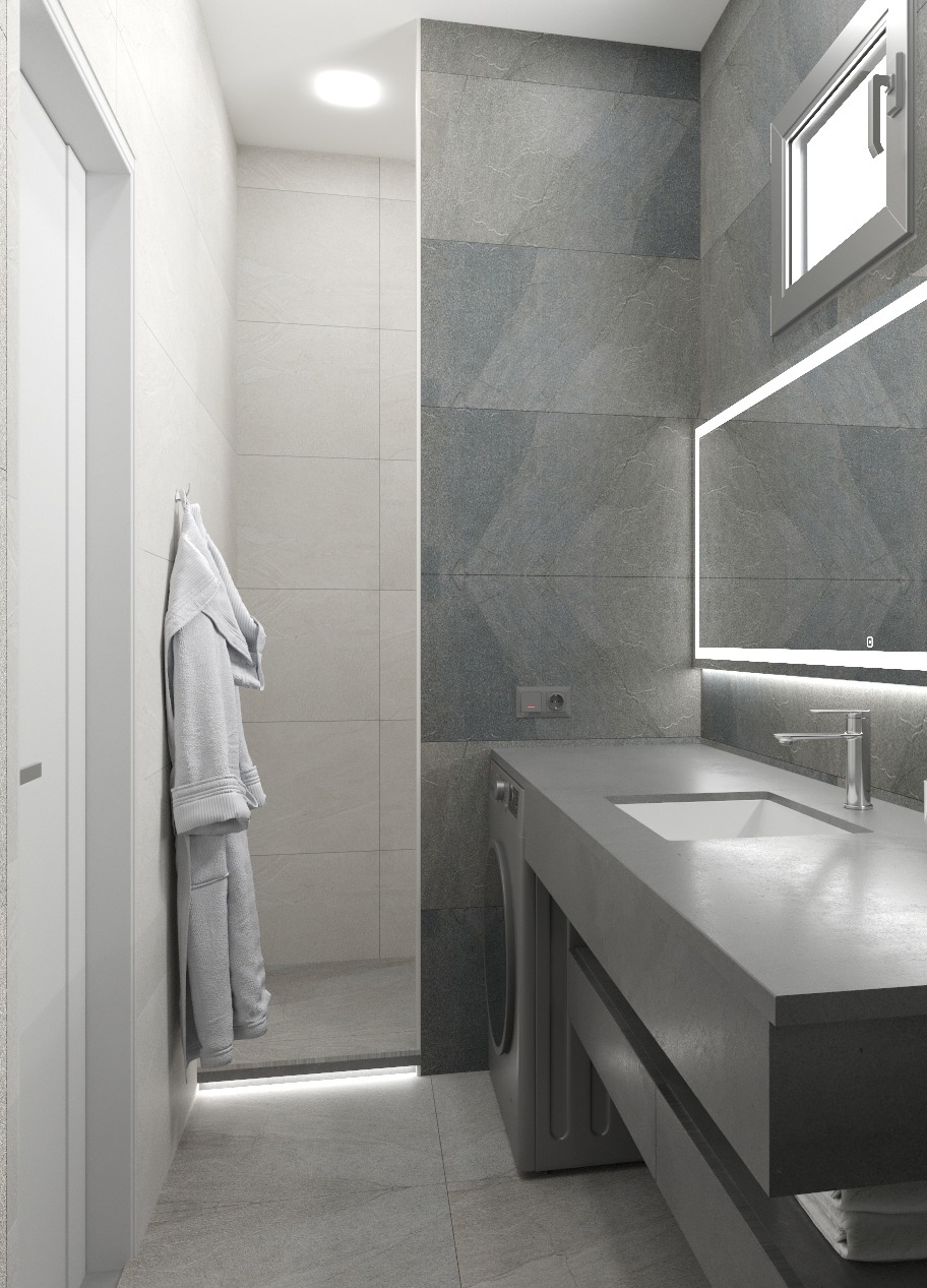 Nowoczesna łazienka z szarymi płytkami imitującymi kamień, podświetlanym lustrem i pralką w zabudowie. Minimalistyczny design z akcentem na funkcjonalność i elegancję.