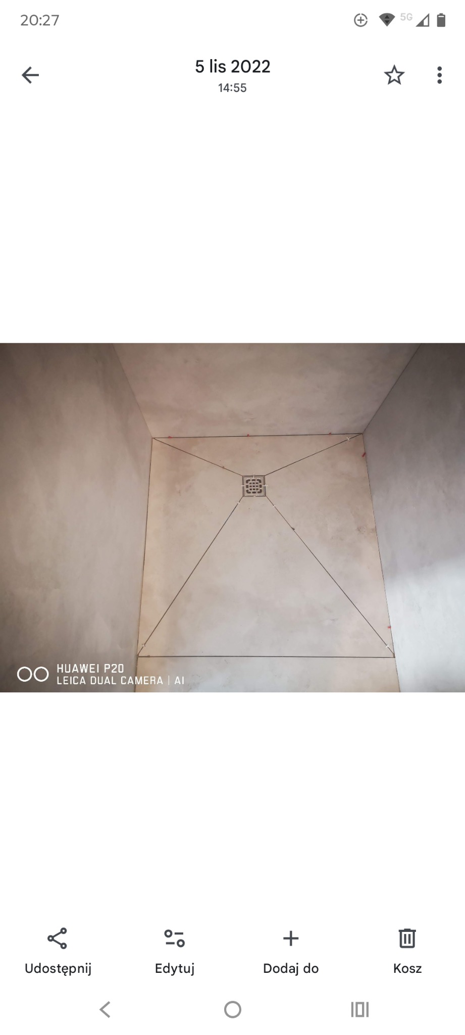 Wykończona posadzka w kabinie prysznicowej z odpływem liniowym. Jasne płytki ułożone ze spadkiem w kierunku odpływu. Widoczne fugi i niewielkie krzyżyki dystansowe.