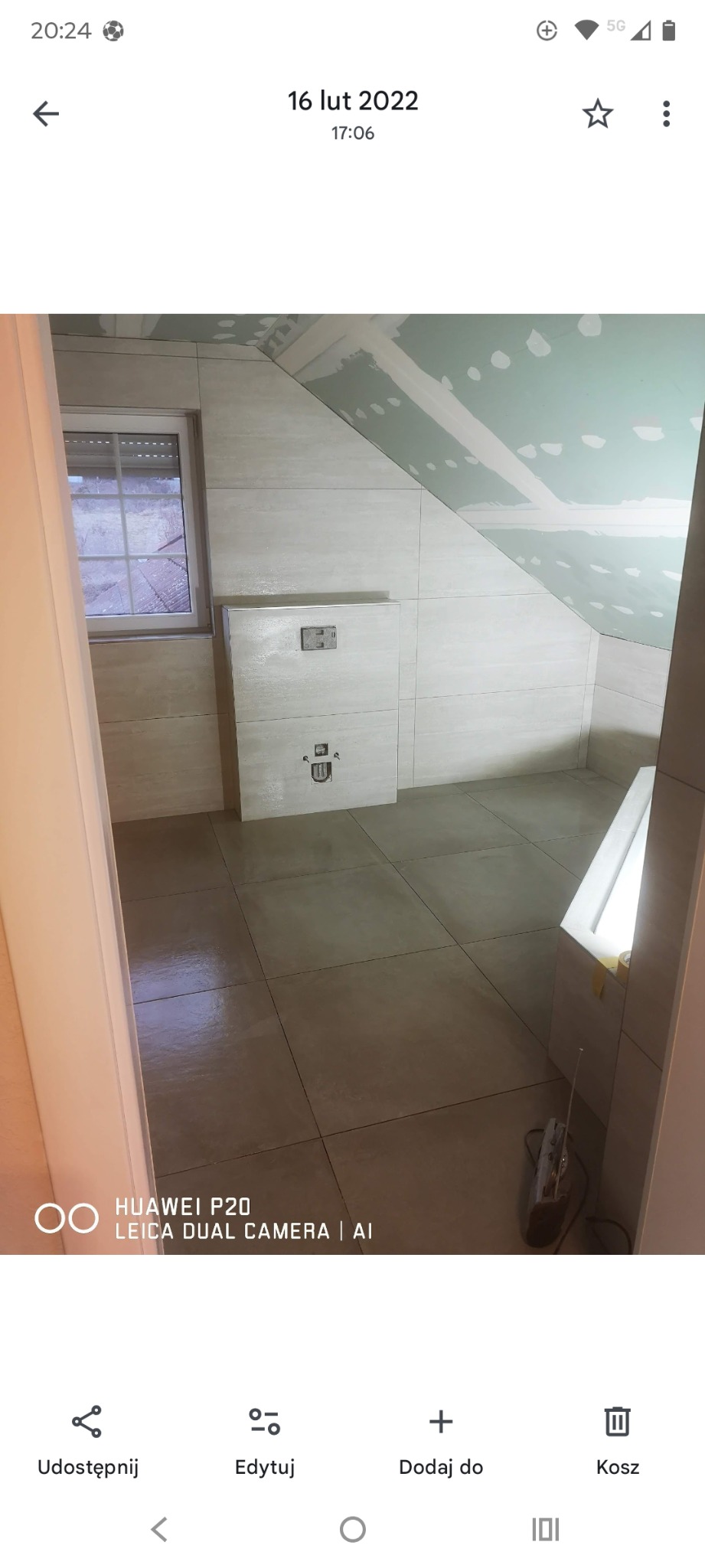 Wykończona łazienka na poddaszu z beżowymi płytkami, zabudową WC i oknem. Ściany i podłoga wyłożone płytkami. Sufit przygotowany do malowania.