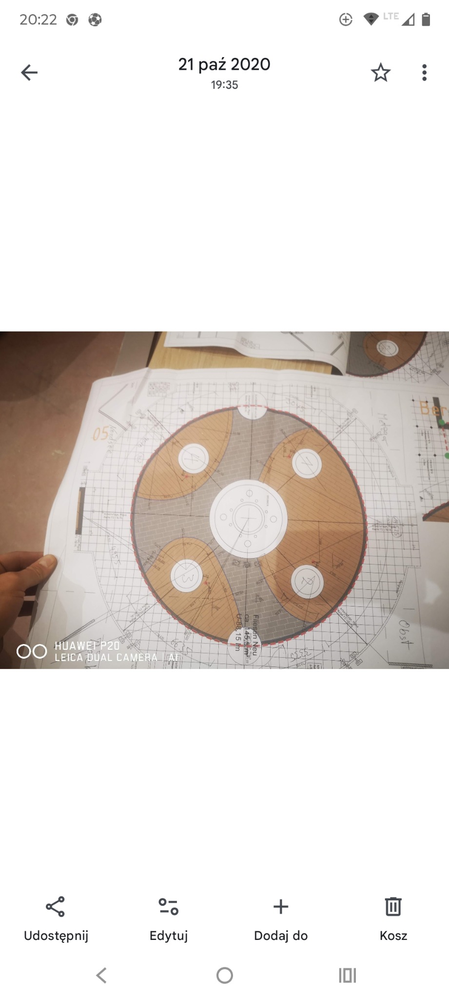 Plan ułożenia płytek z okrągłym wzorem na podłodze, widok z góry. Projekt techniczny z naniesionymi wymiarami i oznaczeniami. Częściowo widoczna dłoń.