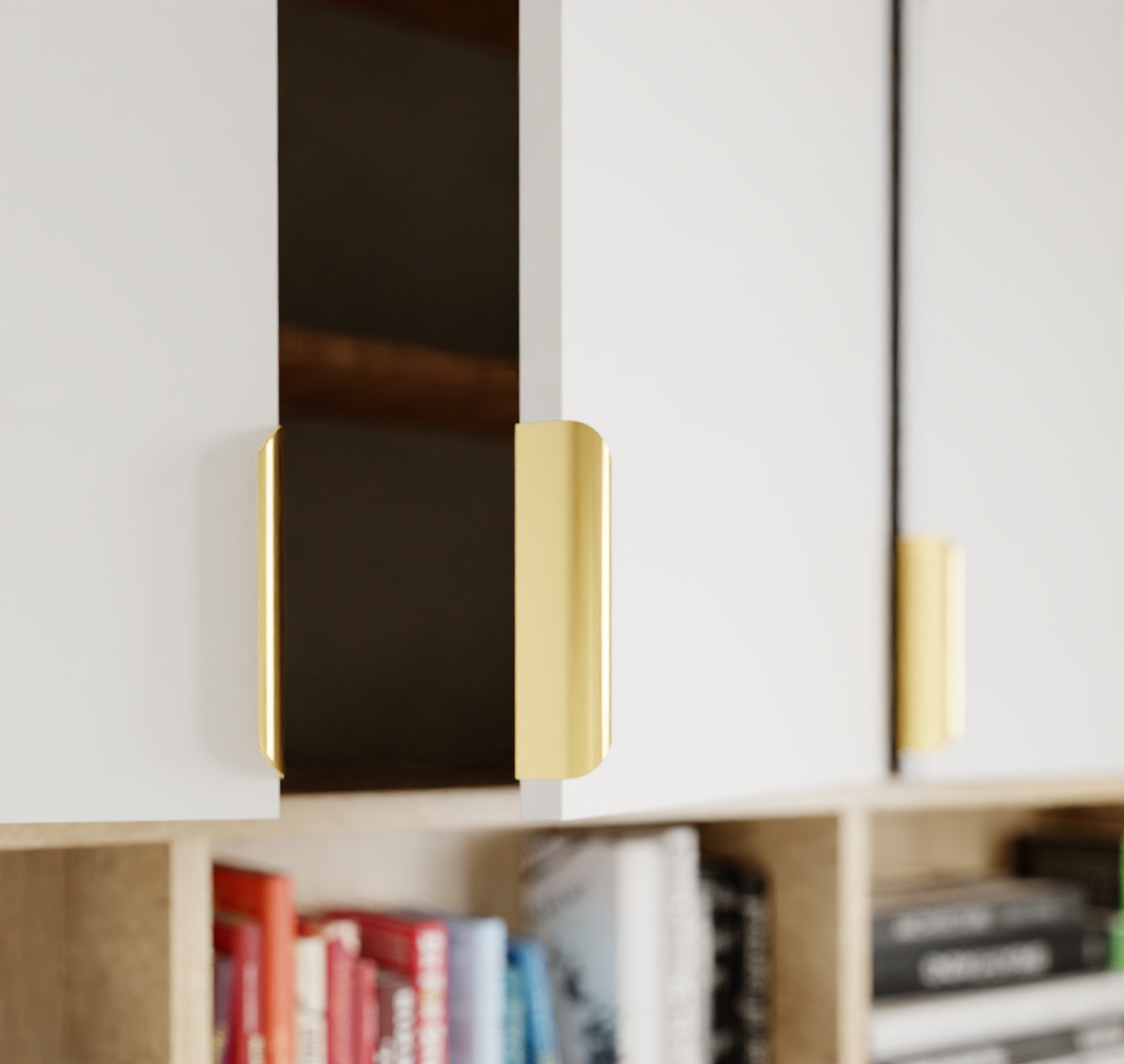 Białe szafki z złotymi uchwytami na tle regału z książkami. Minimalistyczny design, ciepłe oświetlenie, nowoczesne wykończenie wnętrza.