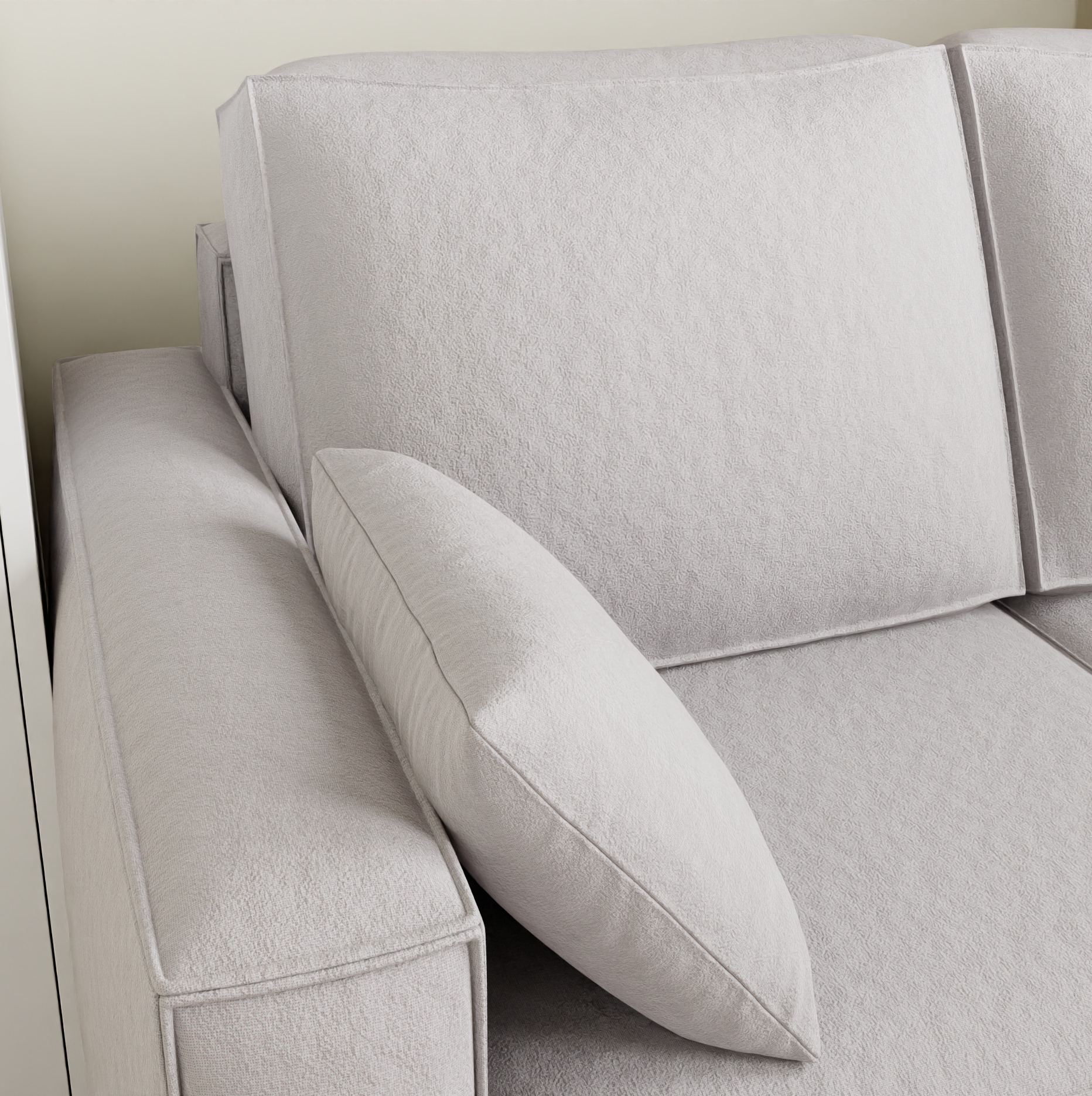 Jasnoszara sofa z poduszką w minimalistycznym stylu, widok z bliska na teksturę materiału i detale wykończenia. Neutralna kolorystyka, nowoczesny design.