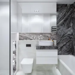 Nowoczesna łazienka z białą ceramiką, umywalką nablatową i ścianą z szarego marmuru ułożonego w jodełkę.