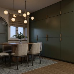Totemi Marta Kowalska - Jadalnia z zabudową Olive Sage: okrągły stół, krzesła z beżową tapicerką, nowoczesna lampa wisząca. Duża szafa w kolorze oliwkowym zajmuje całą ścianę.