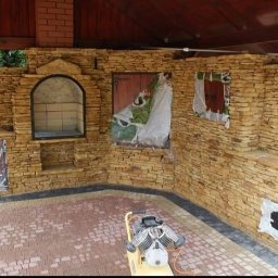 Visual Garden 5.3.0.9.0.8.7.2.8 - Kamienna zabudowa grilla z wędzarnią i kostką brukową. Część elementów zabezpieczona folią. Na pierwszym planie zagęszczarka do kostki brukowej.