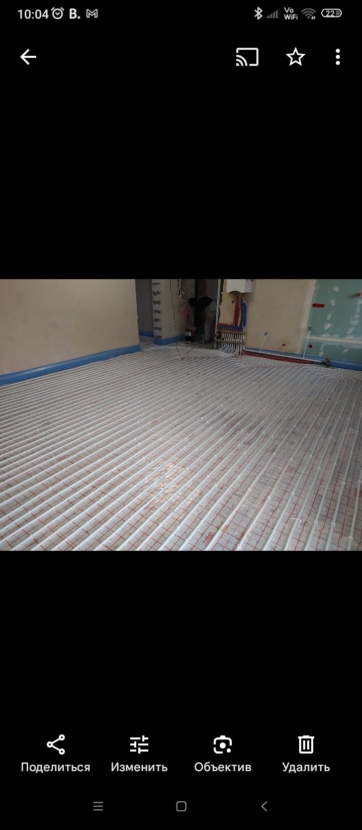 Rozłożona instalacja ogrzewania podłogowego w pomieszczeniu w trakcie prac wykończeniowych. Widoczne rury na folii z siatką, ściany przygotowane do dalszych prac.