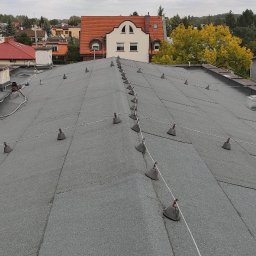 DACH SERWIS Łukasz Lewicki - Dach pokryty papą z zamontowanymi odgromnikami w Ząbkach. Widok z góry na płaską powierzchnię dachu z elementami instalacji odgromowej i kominami wentylacyjnymi.