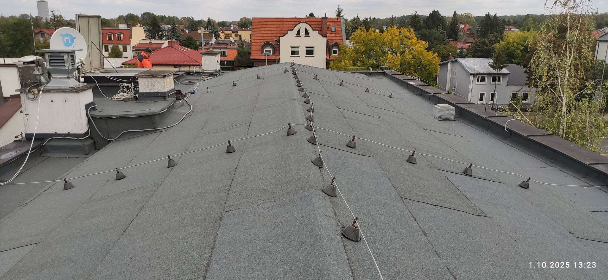 Dach pokryty papą z zamontowanymi odgromnikami w Ząbkach. Widok z góry na płaską powierzchnię dachu z elementami instalacji odgromowej i kominami wentylacyjnymi.
