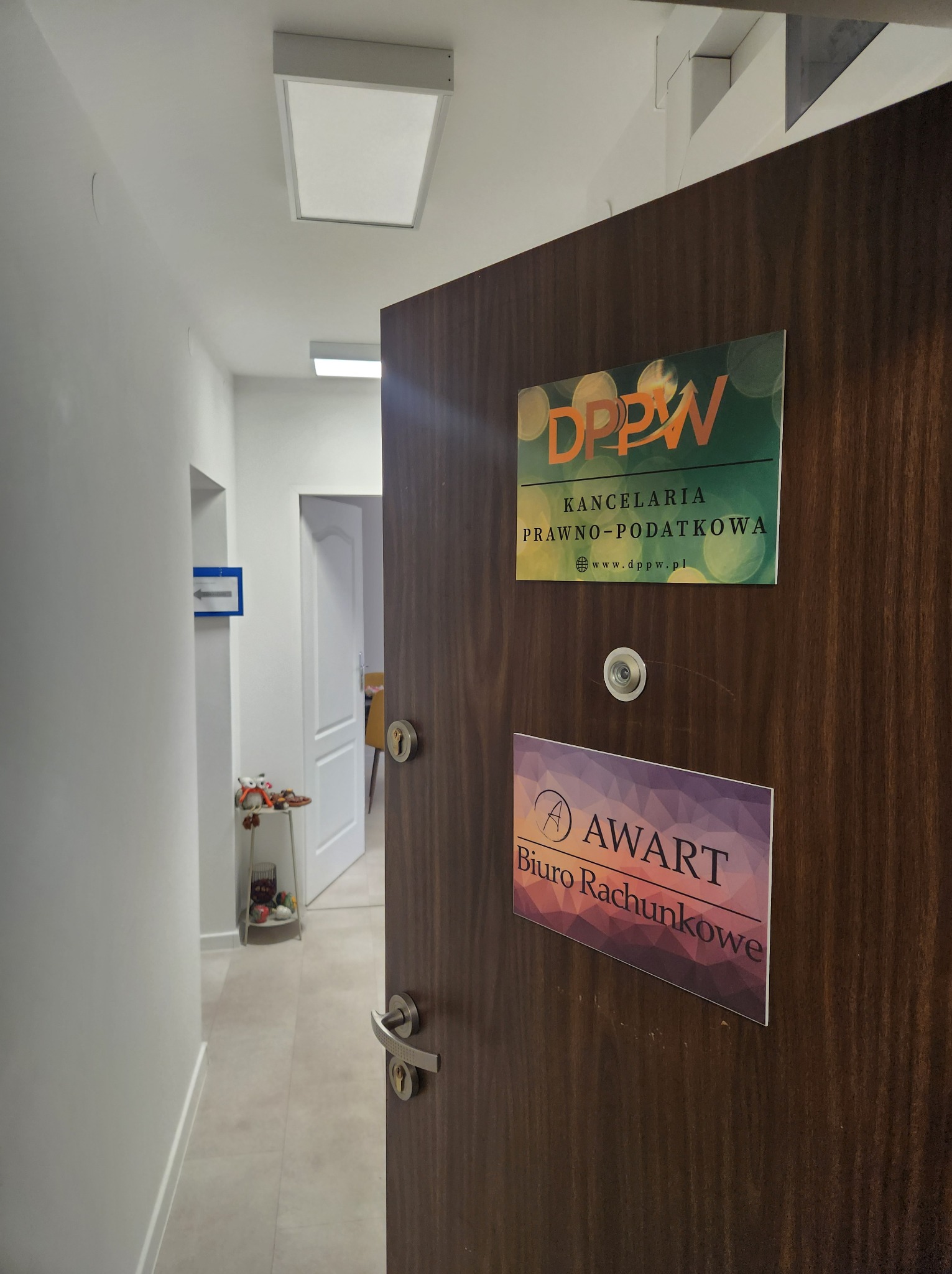 Otwarta, drewniana brama do kancelarii prawno-podatkowej DPPW i biura rachunkowego AWART, z widokiem na korytarz i dekoracje.