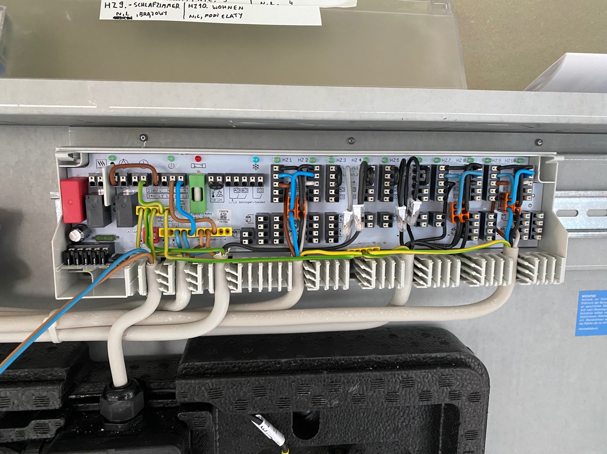 Szczegółowe ujęcie rozdzielnicy elektrycznej z licznymi przewodami w różnych kolorach, podłączonymi do zacisków. Widoczne oznaczenia HZ1-HZ10.