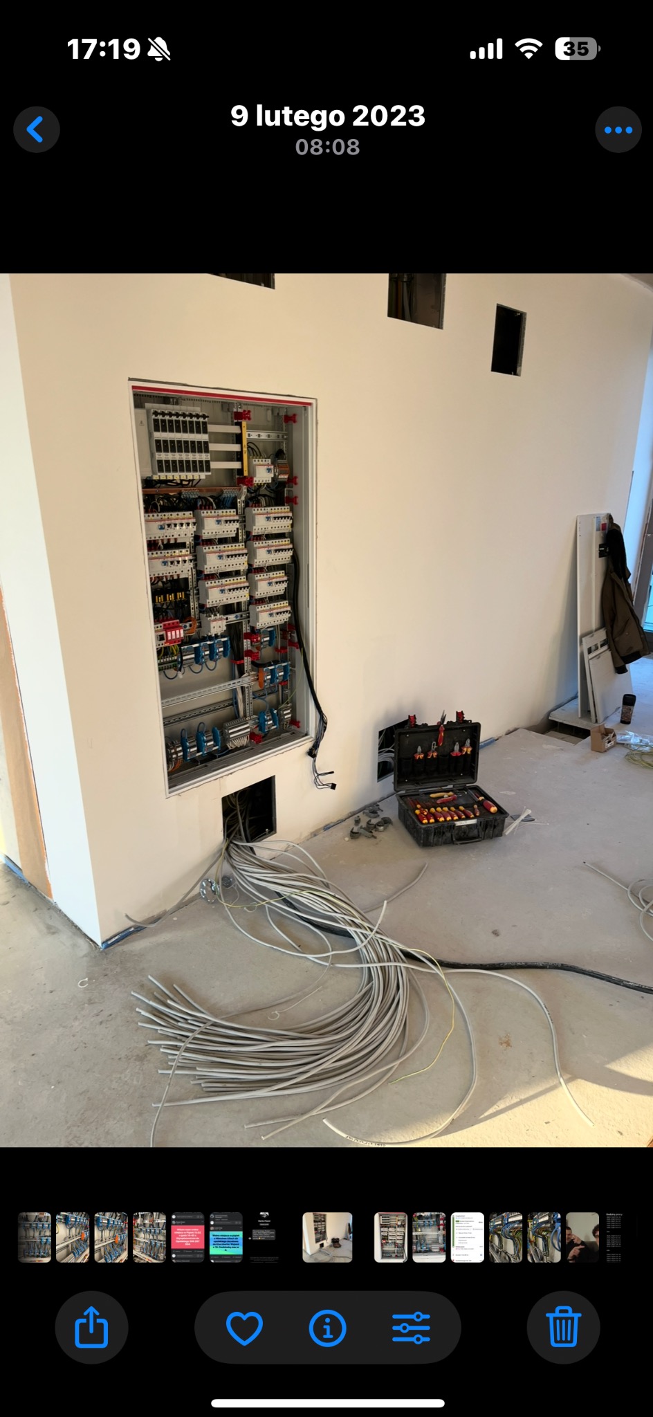 Rozdzielnia elektryczna wnękowa w trakcie montażu, widoczne kable i skrzynka z narzędziami. Surowy stan wykończenia wnętrza.