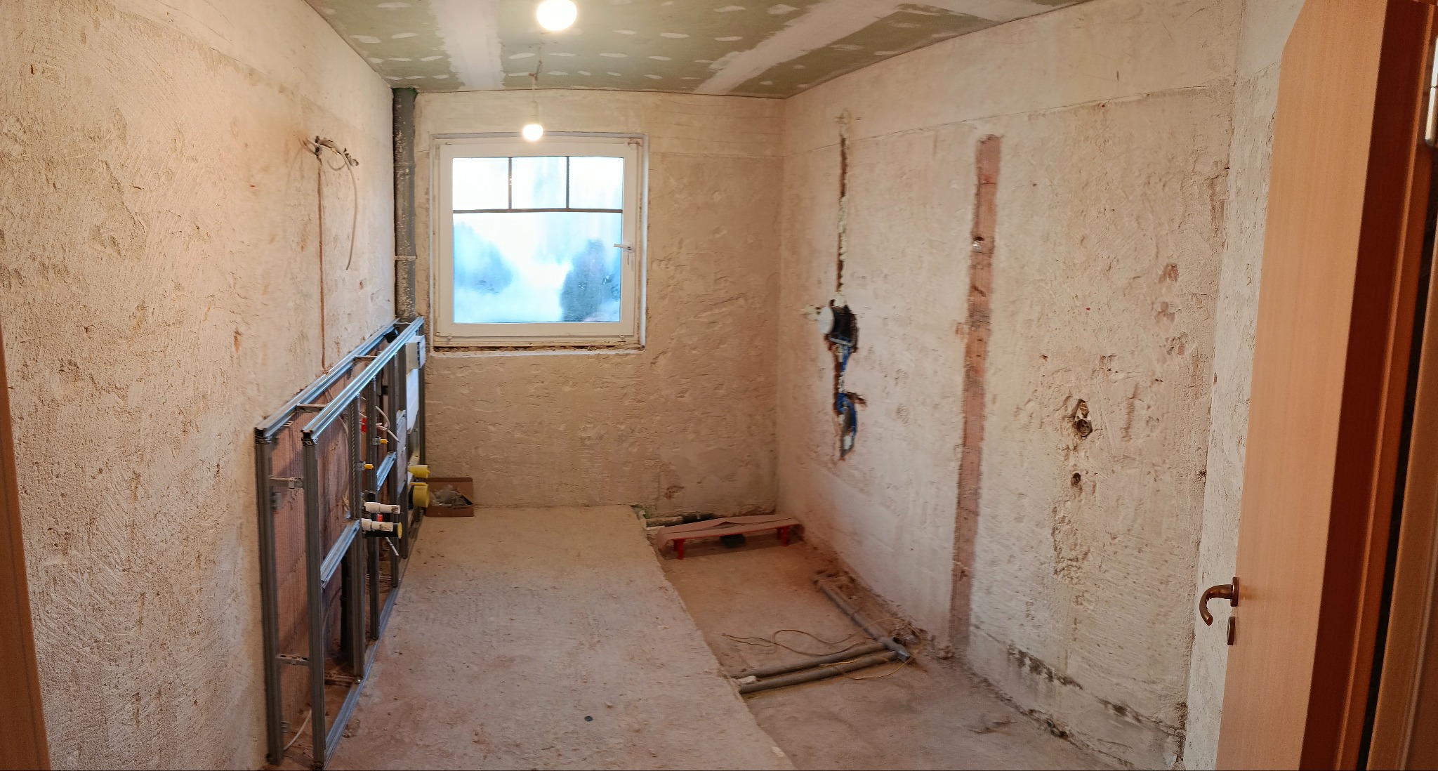 Łazienka w trakcie remontu: widoczne instalacje wodno-kanalizacyjne, surowe ściany z widocznymi przewodami elektrycznymi, przygotowana do dalszych prac wykończeniowych.