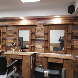 BEBEK, BEBEK MAN BUŁKA I SPÓŁKA DARIUSZ LENART - Barbershop z drewnianymi panelami ściennymi i stanowiskami z lustrami. Widoczne fotele fryzjerskie i oświetlenie sufitowe. Unikalny wystrój wnętrza.