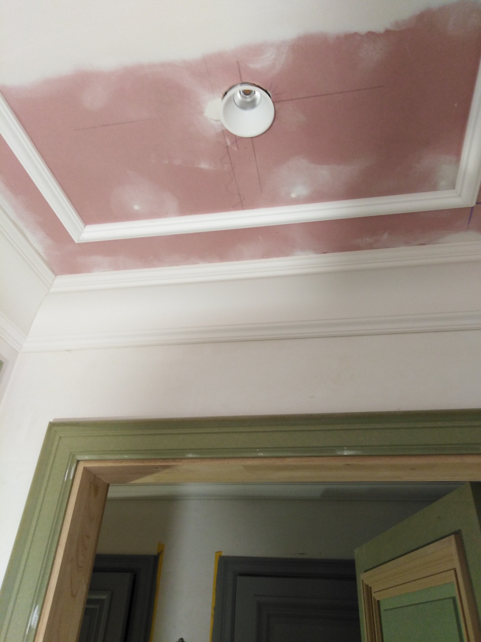 Sufit z dekoracyjną sztukaterią i punktowym oświetleniem w trakcie prac wykończeniowych. Widoczna surowa płyta gipsowa przygotowana do dalszej obróbki, fragment ościeżnicy.