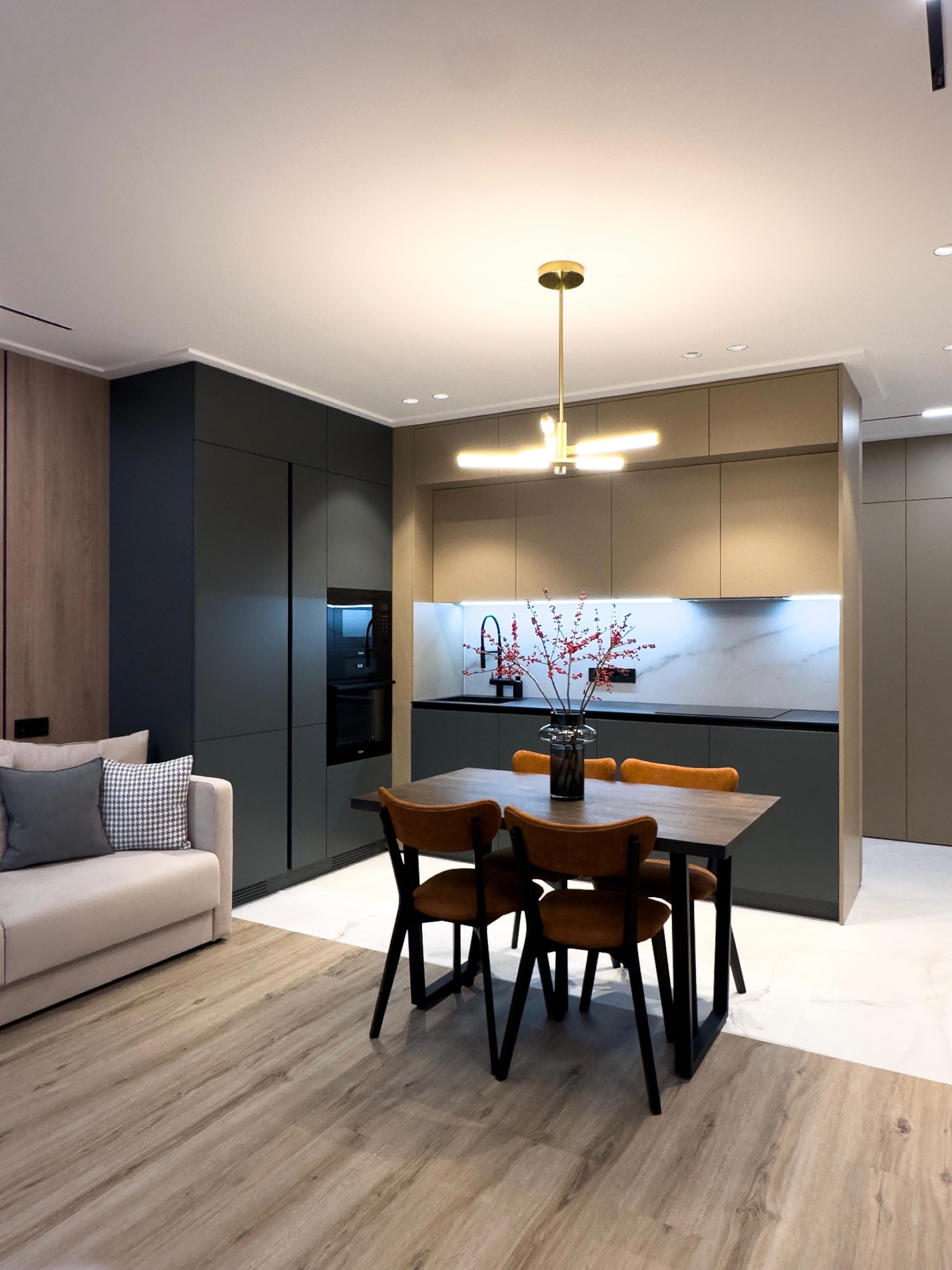 Nowoczesne wnętrze: salon z aneksem kuchennym, drewniana podłoga, stół z krzesłami, minimalistyczne oświetlenie i sufity. Aranżacja z dbałością o detale.
